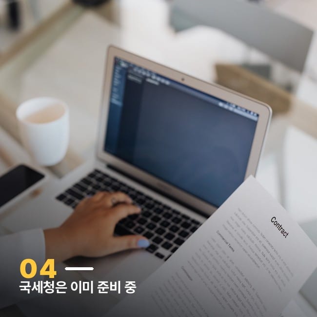 노트북과 서류가 놓인 책상에서 작업하는 손 사진