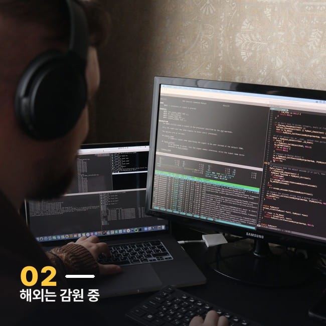 헤드폰을 쓰고 듀얼 모니터로 코드를 보는 개발자 사진
