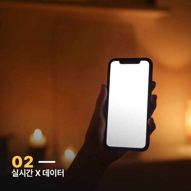 어두운 방 안에서 스마트폰 화면 빛을 받고 있는 손