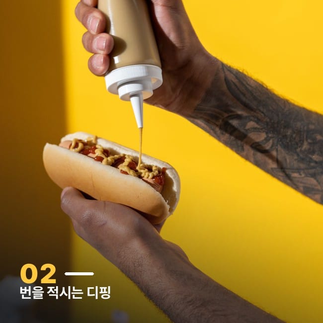머스타드 소스를 뿌리는 손과 핫도그