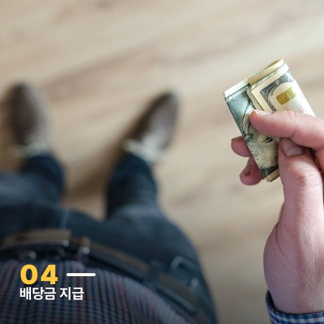 달러 지폐를 손에 든 사람, SPYM ETF 배당금 지급을 상징하는 이미지