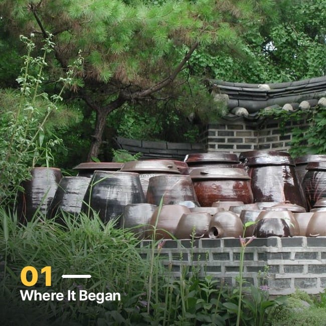 Traditional onggi jars used for fermenting kimchi, stacked outside a hanok wall